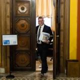 Kokoomuksen puheenjohtaja Petteri Orpo astumassa ulos Säätytalon neuvotteluhuoneen ovesta paperipinkka kainalossaan.