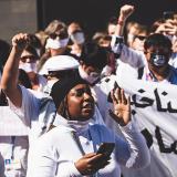 Joukko mielenosoittajia Sharm el-Sheikhissä valkoisten iskulauselakanoiden kanssa, etualalla turbaanipäinen nainen.