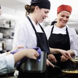 Kolme naista työskentelee ravintolan keittiössä