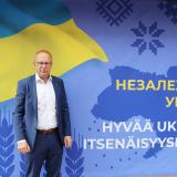 Jarkko Eloranta seisoo Ukrainan itsenäisyyspäivää juhlistavan ison banderollin edessä SAK:n keskustoimiston edessä. Banderollissa teksti Hyvää Ukrainan itsenäisyyspäivää suomeksi ja ukrainaksi.