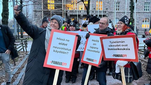 Katja Syvärinen ottaa ryhmä-selfietä, jossa ovat mukana Jarkko Eloranta ja Annika Rönni-Sällinen mielenosoituskyltit kädessään.