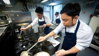 Filippiiniläisiä kokkeja työssä ravintolan keittiössä.