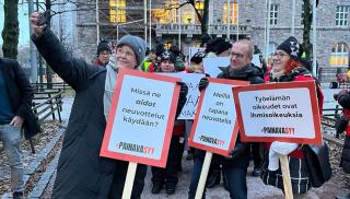 Katja Syvärinen ottaa ryhmä-selfietä, jossa ovat mukana Jarkko Eloranta ja Annika Rönni-Sällinen mielenosoituskyltit kädessään.