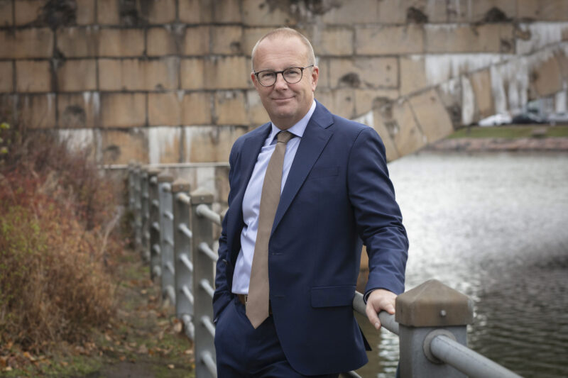 Jarkko Eloranta nojaa merenrannalla olevaan kaiteeseen, taustalla näkyy merenlahden ylittävän sillan muurausta.