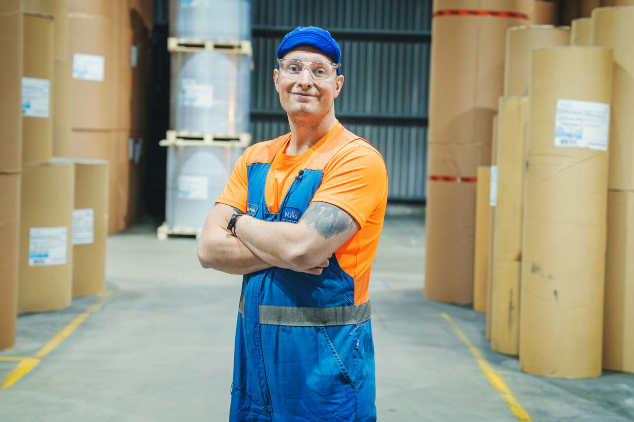 Marko Koivuranta seisoo paperirullapinojen edessä ja katsoo suoraan kameraan.