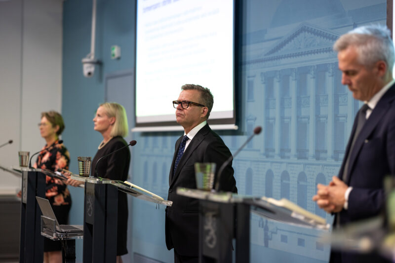 Neljä hallituspuolueiden puheenjohtajaa seisoo mikrofonien äärellä.