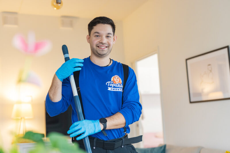 Vastaava kodinhoitaja Anton Manninen seisoo pidellen pitkävartista lattianpyyhintä ja katsoo suoraan kameraan.