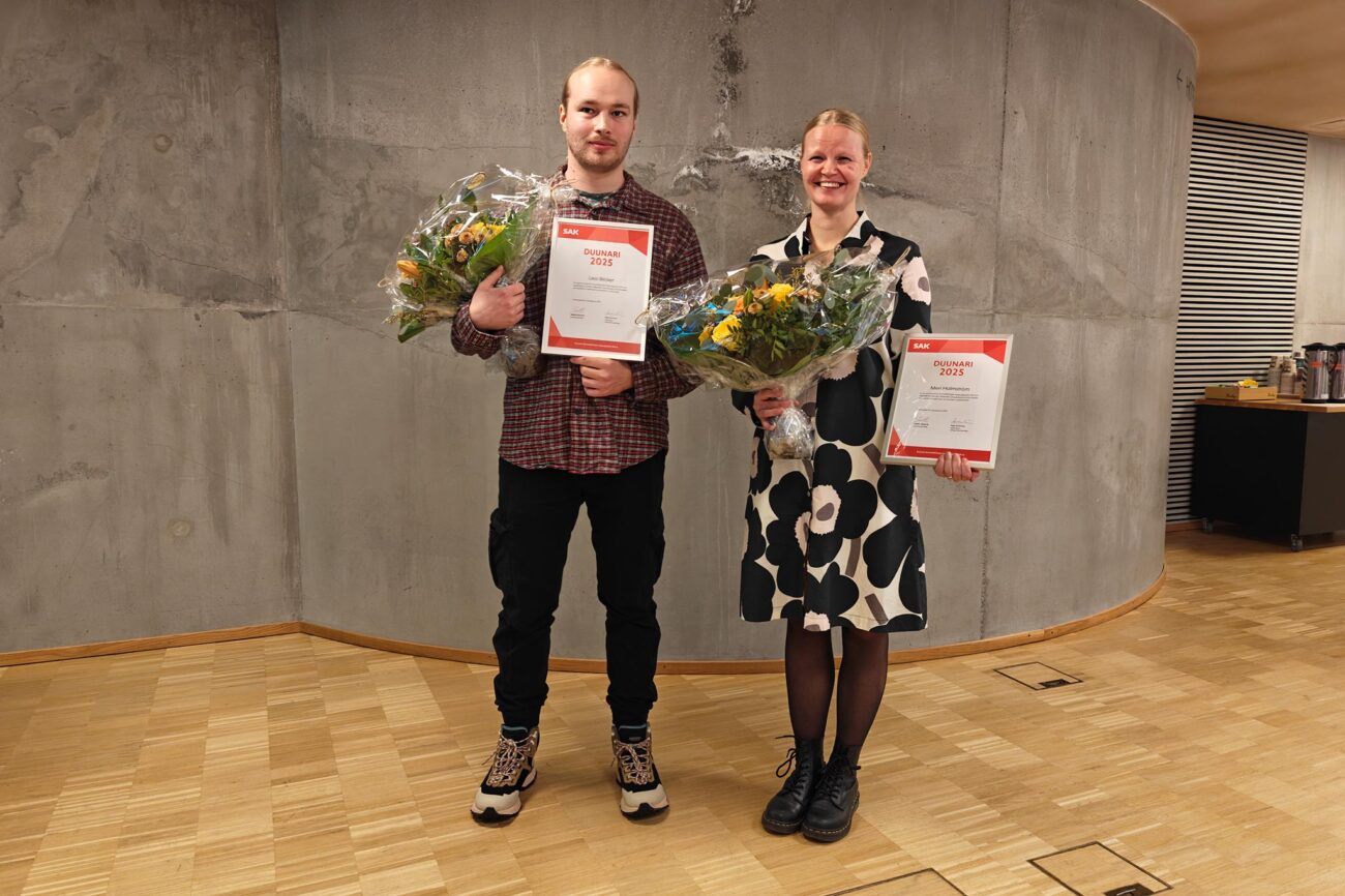 Lassi Becker ja Meri Holmström seisovat vierekkäin kukat ja Vuoden duunari -kunniakirjat käsissään.