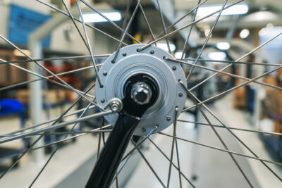 Lähikuva polkupyörän renkaan navasta ja pinnoista, taustalla näkyy pyörien kokoonpanohallia.