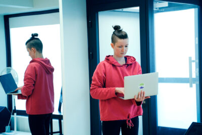 Pau Kettunen seisoo tanssisalin uloskäynnin edessä kannettava tietokone käsissään.