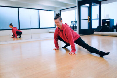 Pau Kettunen on tanssisalissa kädet tuettuna lattiaan ja toinen jalka levitettynä sivulle.