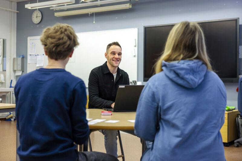 Eero Uotila ja kaksi oppilasta pöydän ääressä.