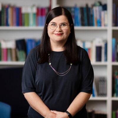 Puolivartalokuva Sanna Mannosesta kirjahyllyn edessä.