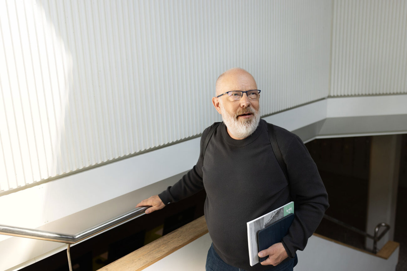 Mies nousee portaita kirja ja monisteitä kainalossa.