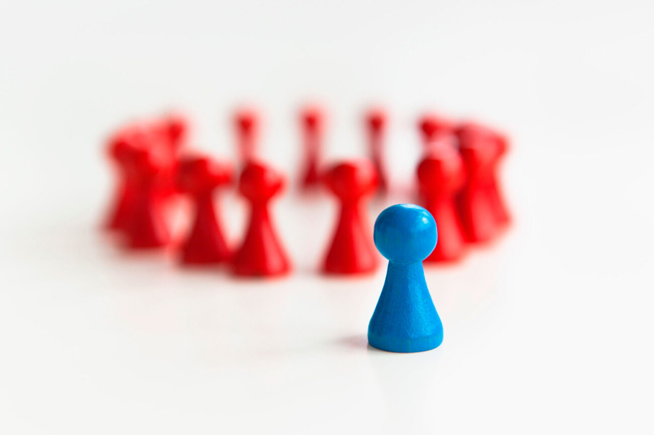 punaisia pelinappuloita ringissä ja edessä sininen pelinappula.