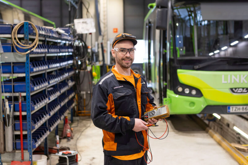 Jonas Huwiler puolivartalokuvassa taustalla sähköbussi.