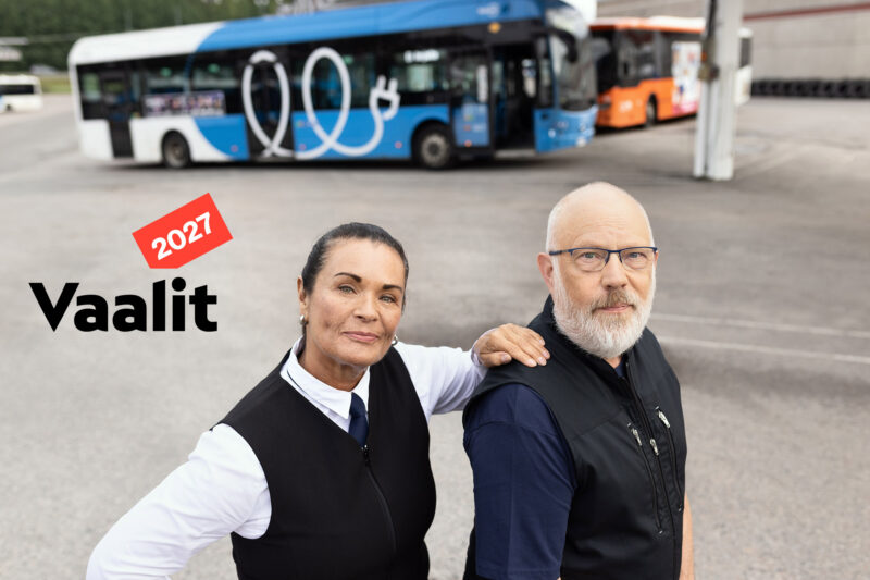 Bussikuski ja siivooja seisovat bussien edessä ja bussikuski pitelee kättään siivoojan olkapäällä, vieressä Vaalit 2027 -logo.