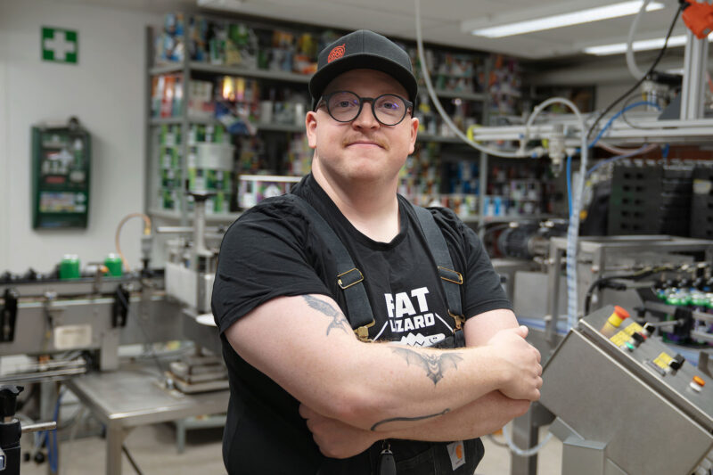 Mikko McLean står med armarna i kors framför bryggeriets utrustning.