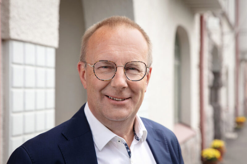 Jarkko Elorannan kasvokuva ulkona vaalean rakennuksen edessä.